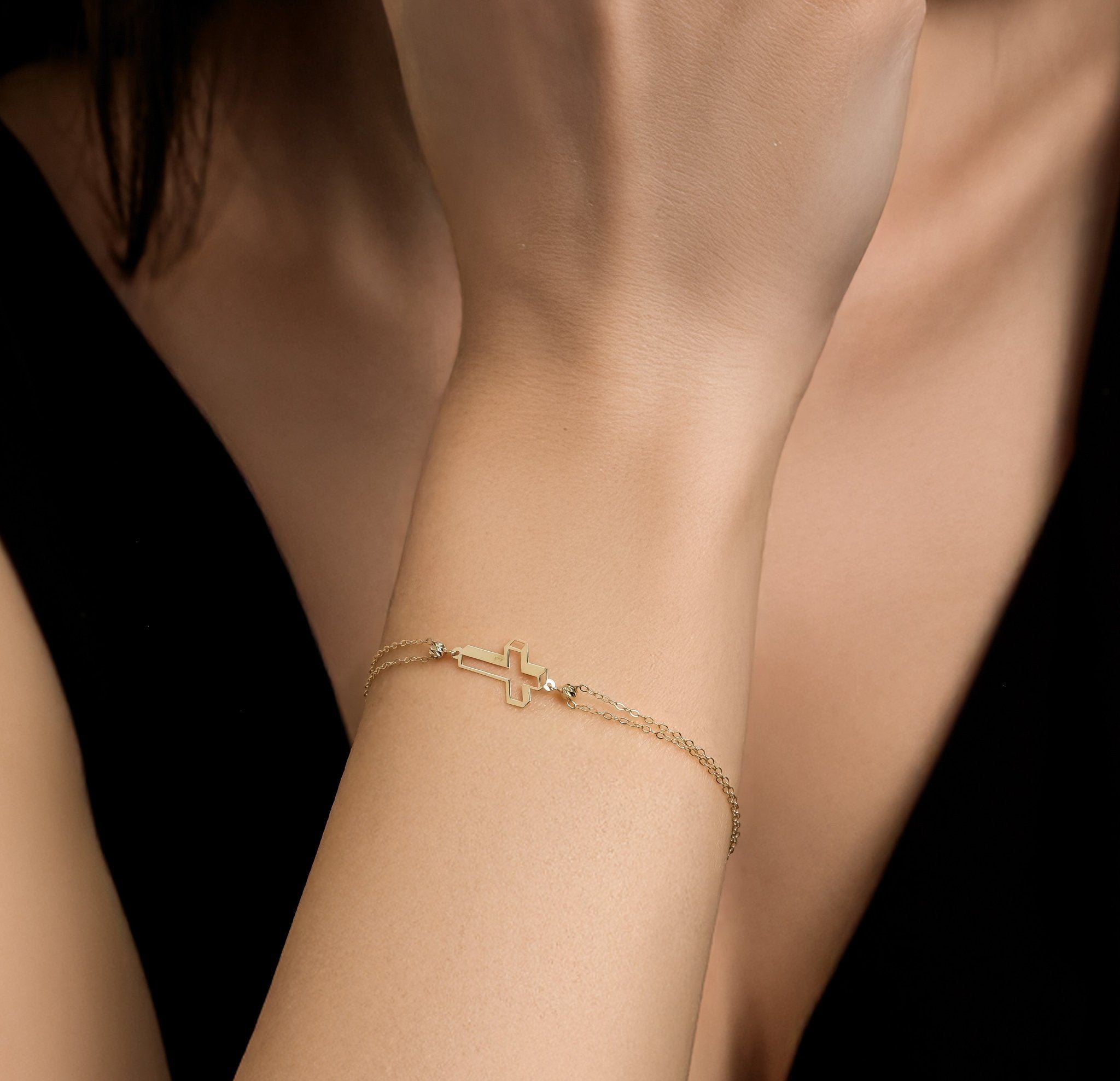 Dainty 14K solid yellow gold 3D small cross bracelet worn on wrist, elegant design, perfect for everyday use.