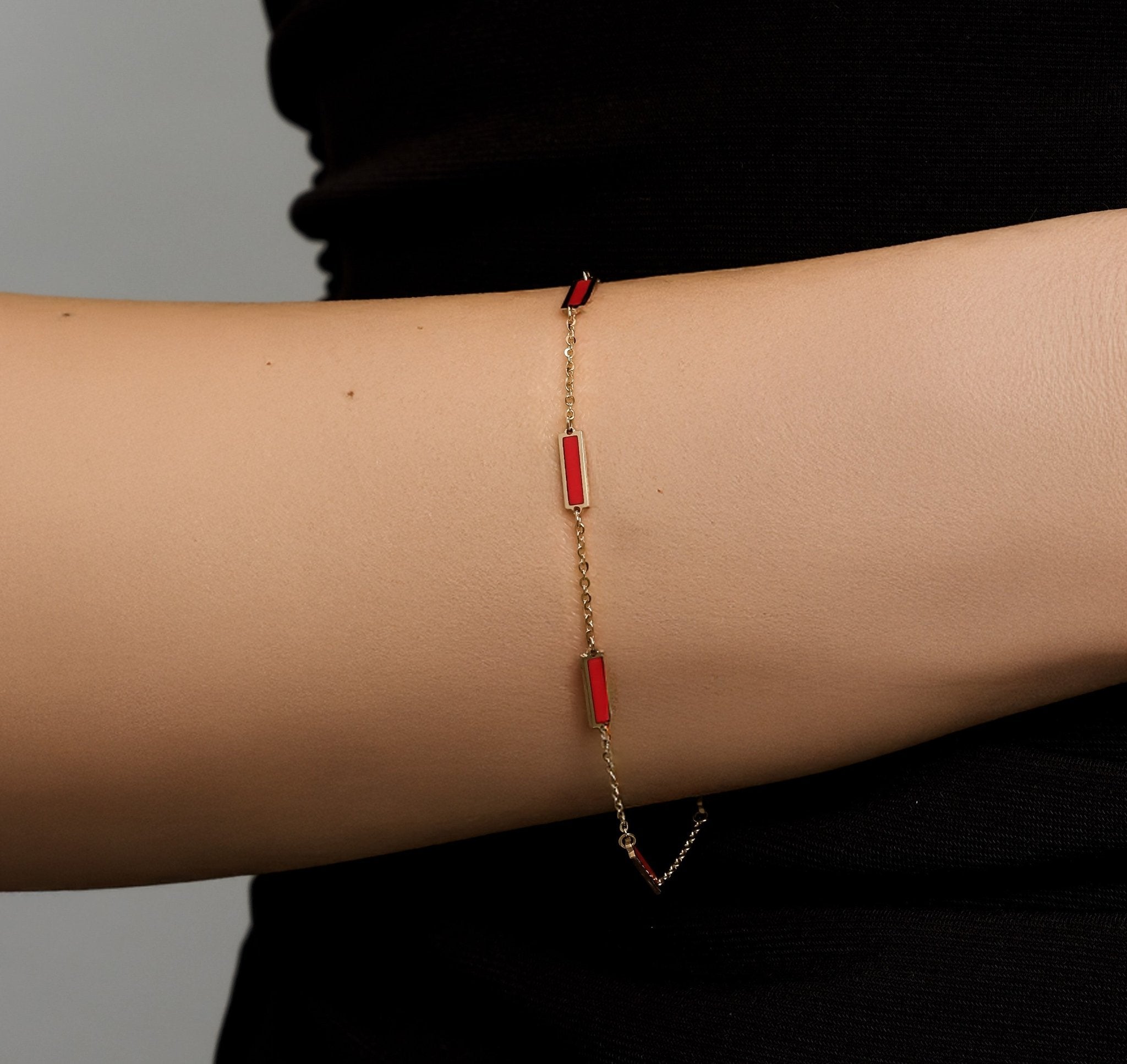 14K solid yellow gold bracelet with red coral bars, 7 inches long, elegantly displayed on a model's wrist.