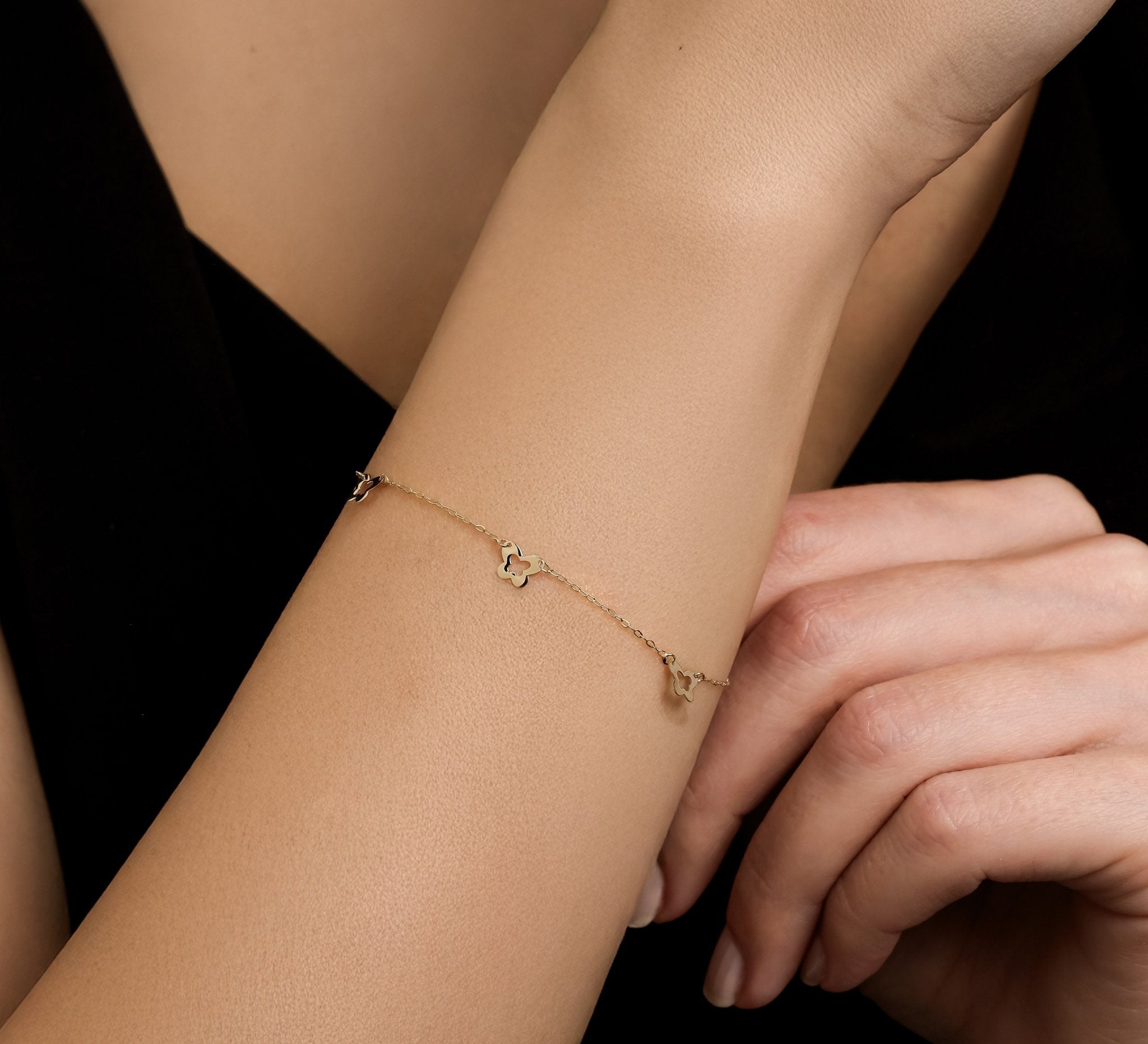 14K solid yellow gold small butterfly station bracelet worn on the wrist, showcasing its delicate design and elegance.