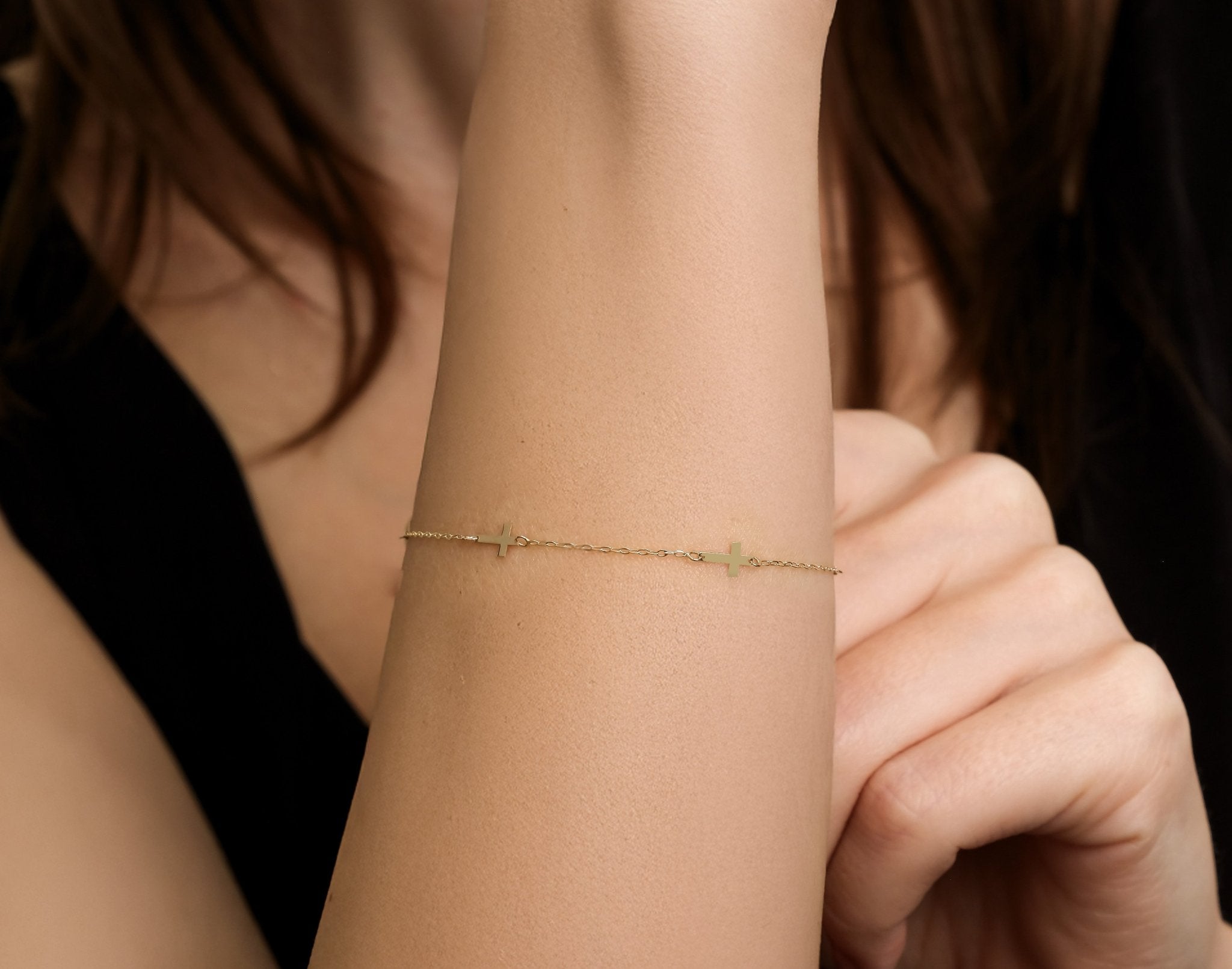 14K solid yellow gold small cross station bracelet worn on wrist, showcasing delicate design and dainty elegance.