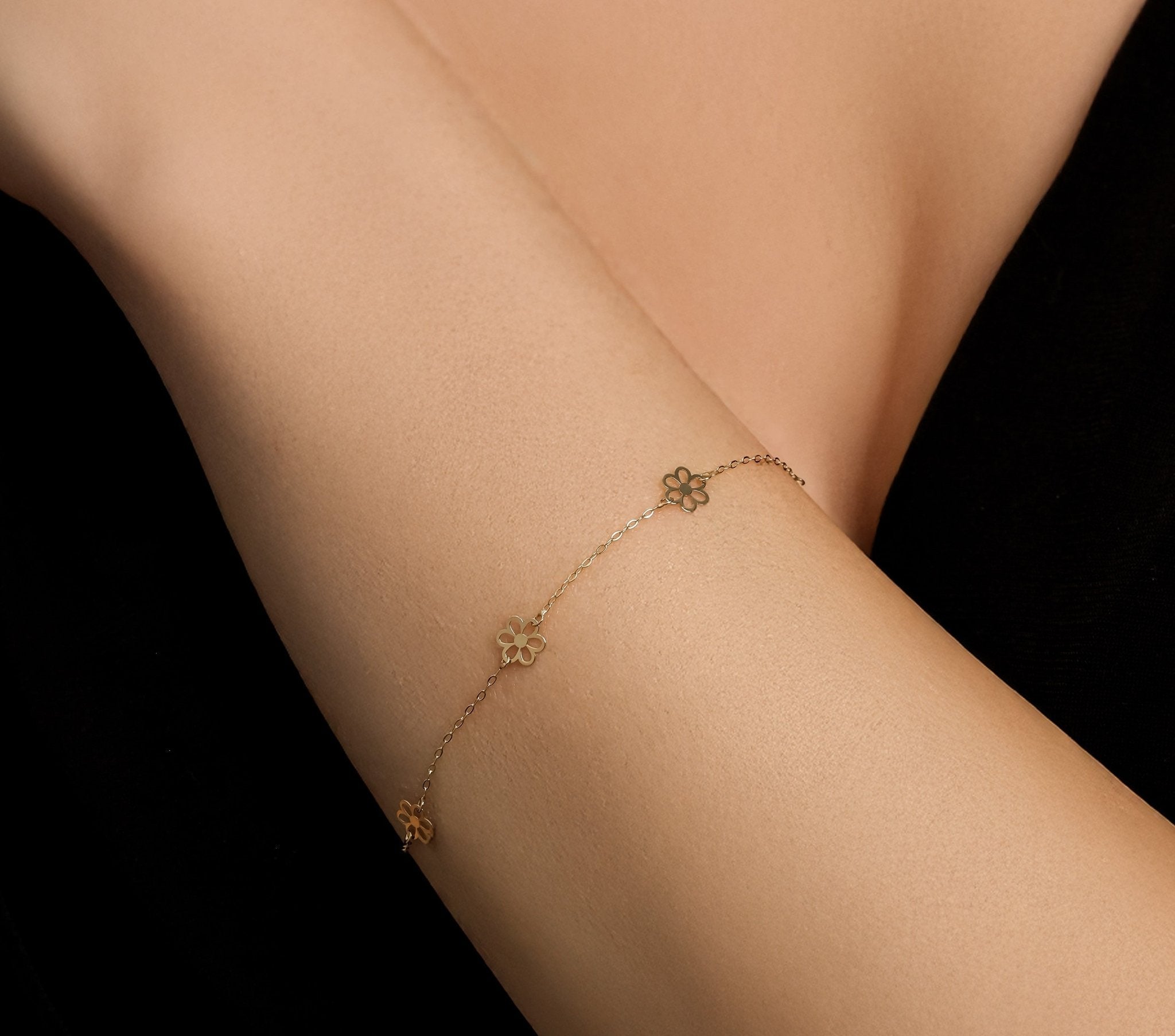 14K solid yellow gold small daisy flower station bracelet on a woman's wrist, showcasing delicate design and elegance.