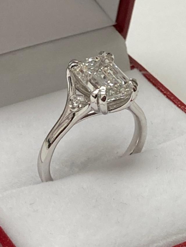 14K white gold emerald cut diamond engagement ring with side diamonds in a jewelry box, shiny finish.