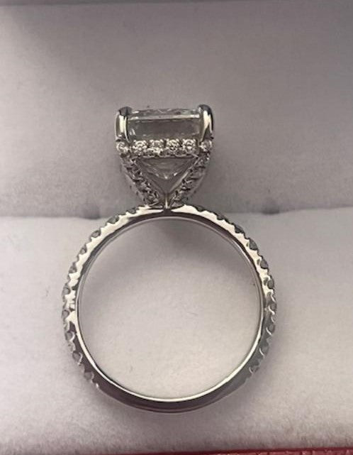 14K white gold engagement ring featuring a 4ct emerald cut lab diamond and diamond side stones, displayed on a soft background.