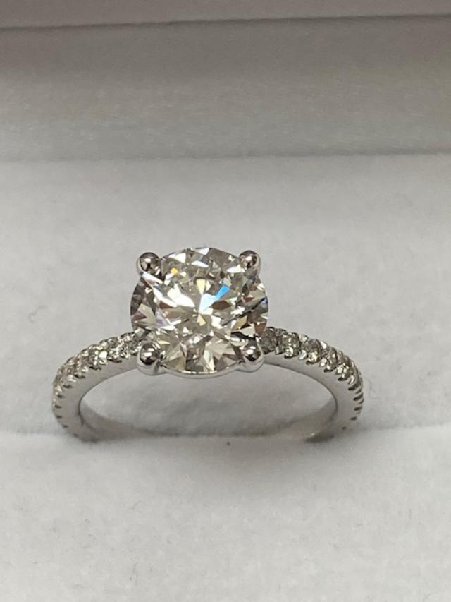14K white gold round cut lab diamond engagement ring with sparkling side stones on a plush background.