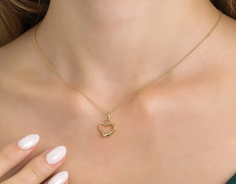 Dainty 14K yellow gold minimalist heart necklace worn on neckline, perfect for everyday use.