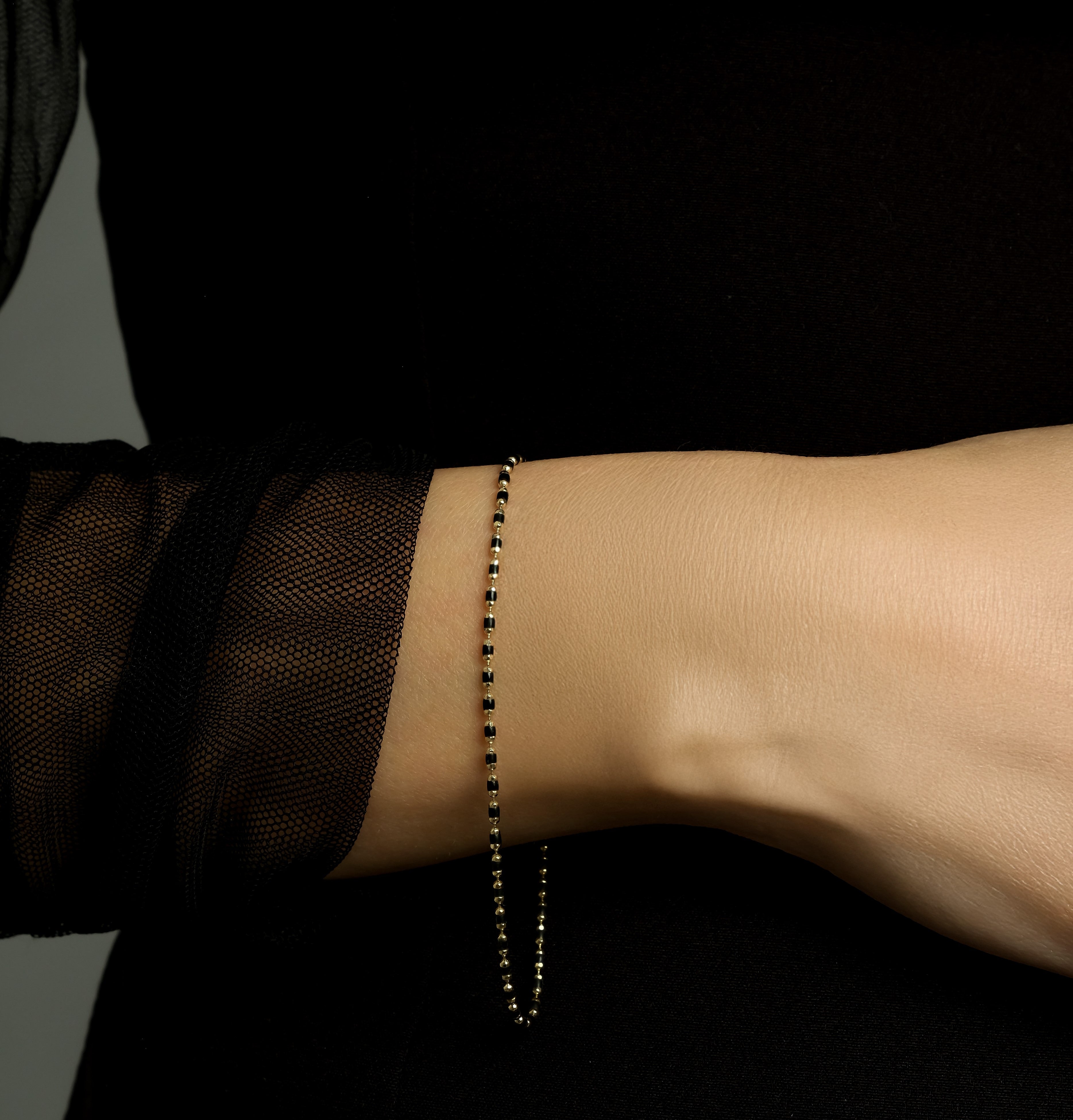 14K yellow gold black enamel beaded bracelet worn on wrist, showcasing its dainty and classy design.