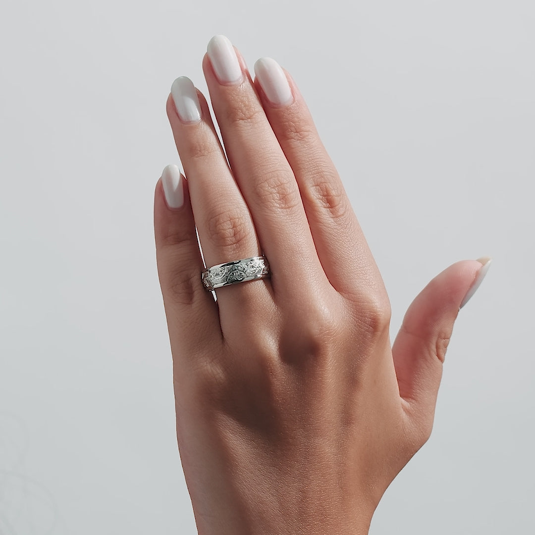 Hand model wearing a 7mm solid white gold hand engraved wedding band with leaf motif.