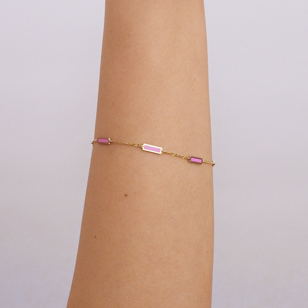 14K solid yellow gold pink bar bracelet worn on an arm, featuring a delicate design and lobster claw clasp.