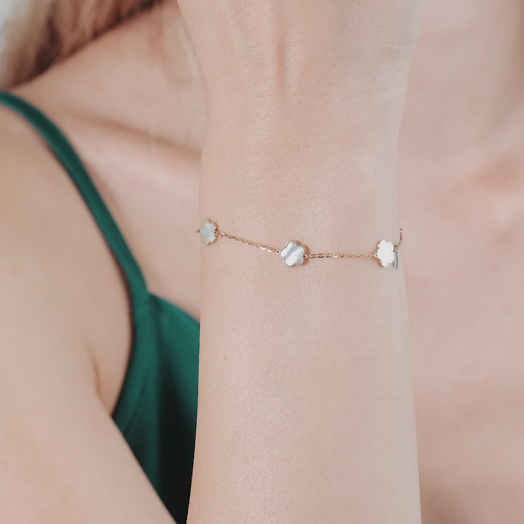 14K yellow gold mother of pearl daisy flower bracelet worn on a wrist, showcasing delicate floral design.