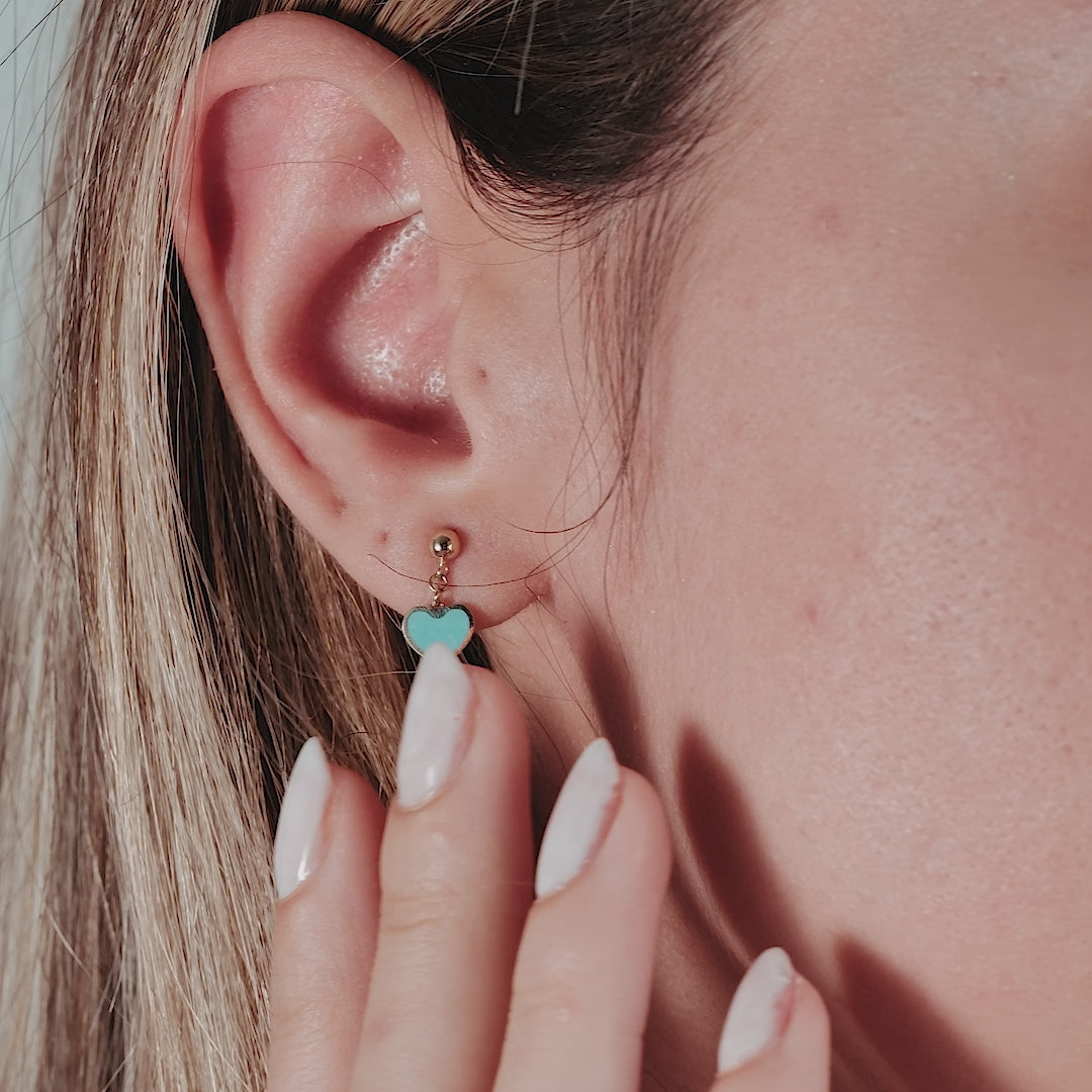 14K yellow gold turquoise dangle heart earrings worn by a model, showcasing a minimalist design and vibrant color.