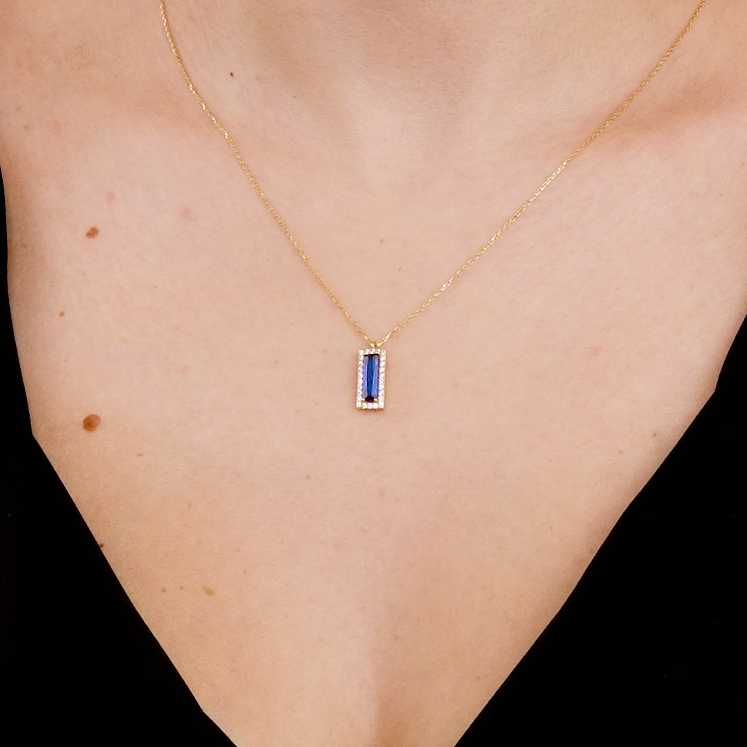 14K solid yellow gold baguette sapphire necklace worn elegantly, featuring a stunning blue sapphire pendant.