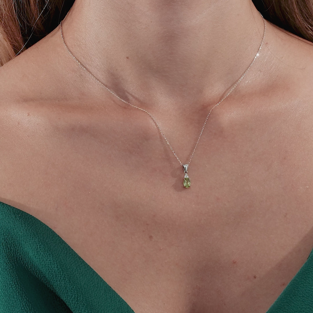 Model wearing a 14K white gold natural peridot and diamond solitaire necklace on a delicate chain.