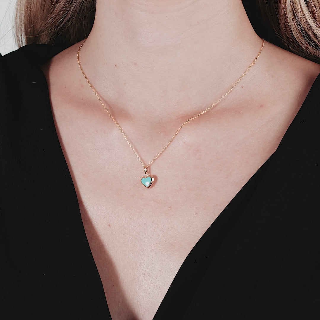 14K yellow gold minimalist necklace featuring a turquoise puffed heart pendant worn by a model.