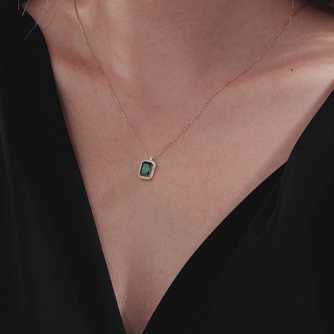 14K yellow gold emerald cut solitaire emerald necklace worn on model's neck, showcasing simple elegance and sophistication.