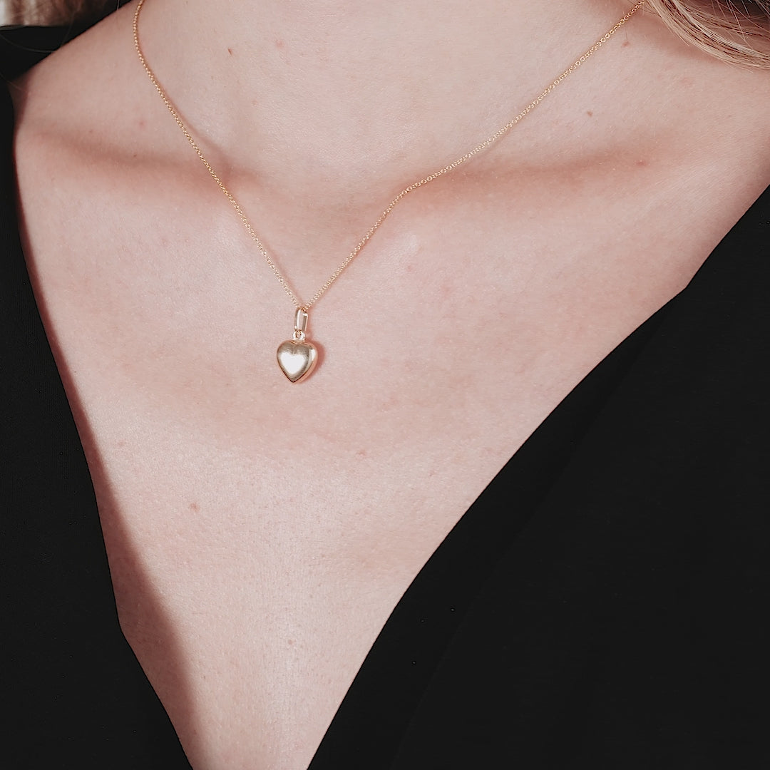 Model wearing a 14K yellow gold shiny puffed heart necklace, showcasing its simple and elegant design.