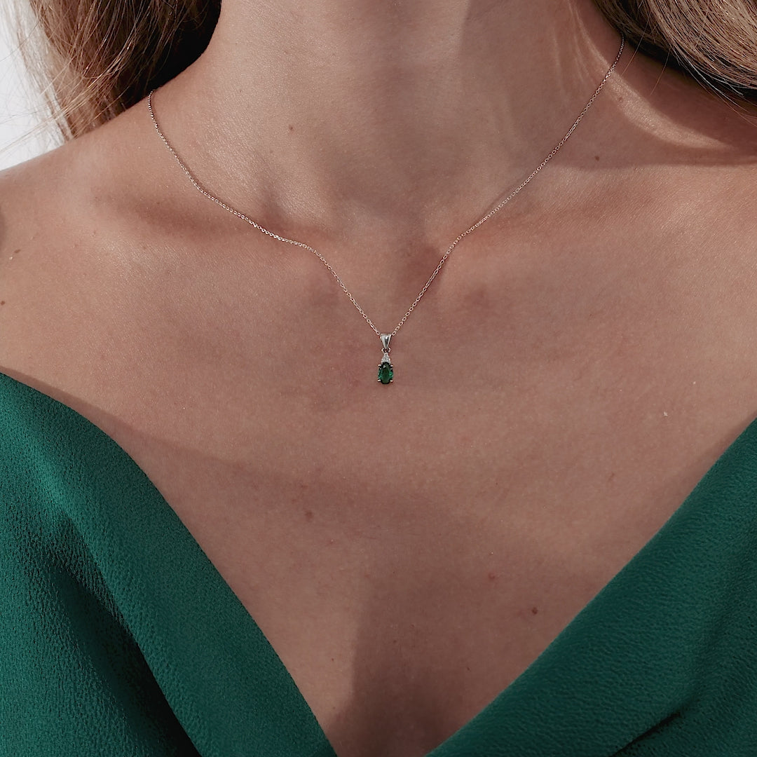 Model wearing a 14K white gold solitaire necklace featuring an emerald pendant and delicate chain.