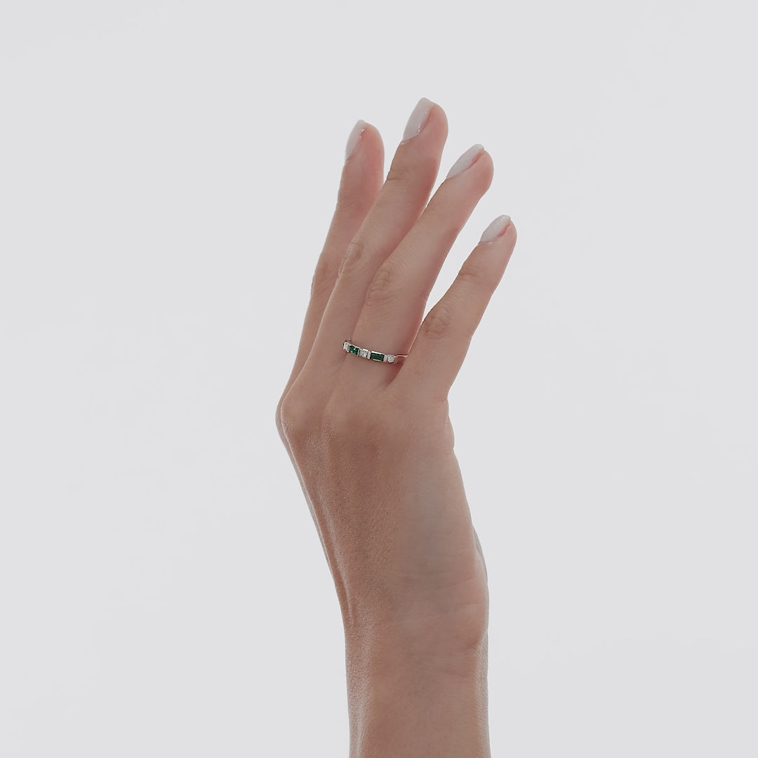 Hand wearing a dainty 14K solid white gold emerald and diamond wedding ring, showcasing its elegant design.
