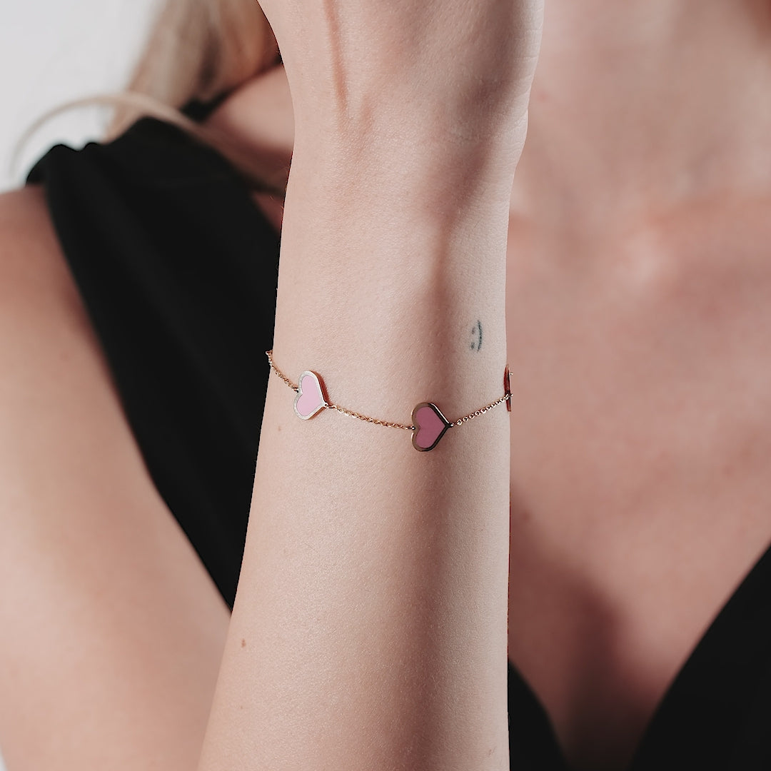 14K solid yellow gold bracelet with pink hearts, model wearing it on wrist, perfect gift in a stylish presentation.