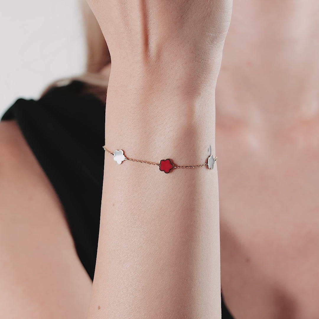 14K yellow gold bracelet with red coral and mother of pearl blossoms on a wrist, showcasing elegance and simplicity.