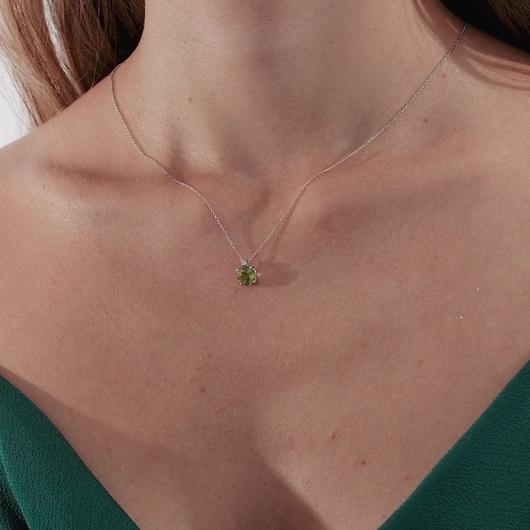 Model wearing a 14K solid gold necklace featuring a natural peridot gemstone in a delicate setting.