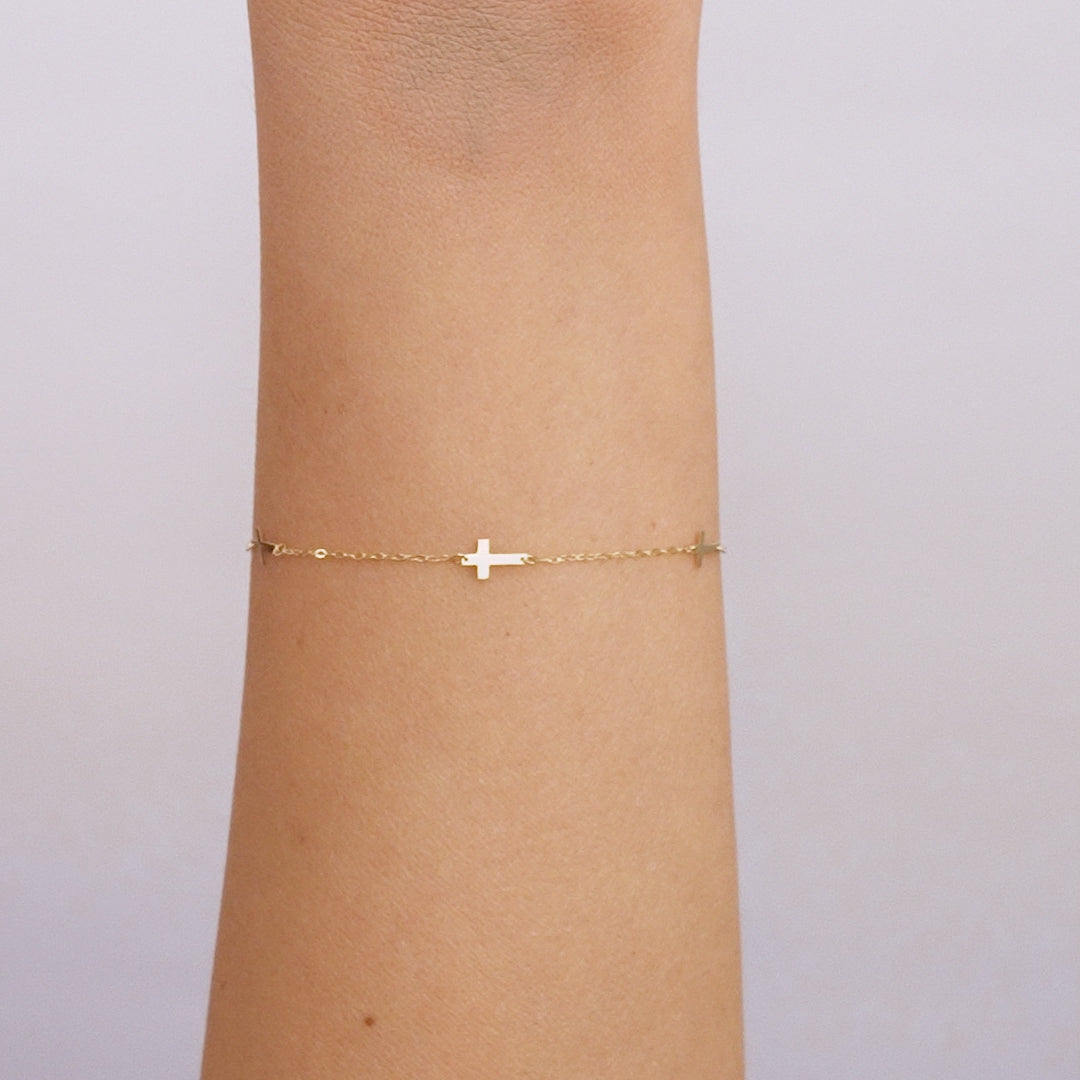 Dainty 14K solid yellow gold small cross station bracelet on wrist, measuring 7 inches, perfect for everyday wear.