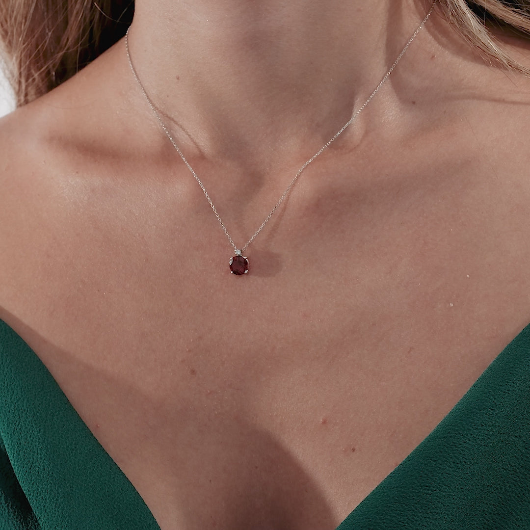 Dainty 14K white gold natural garnet and diamond solitaire necklace worn on a woman, showcasing its elegance and beauty.