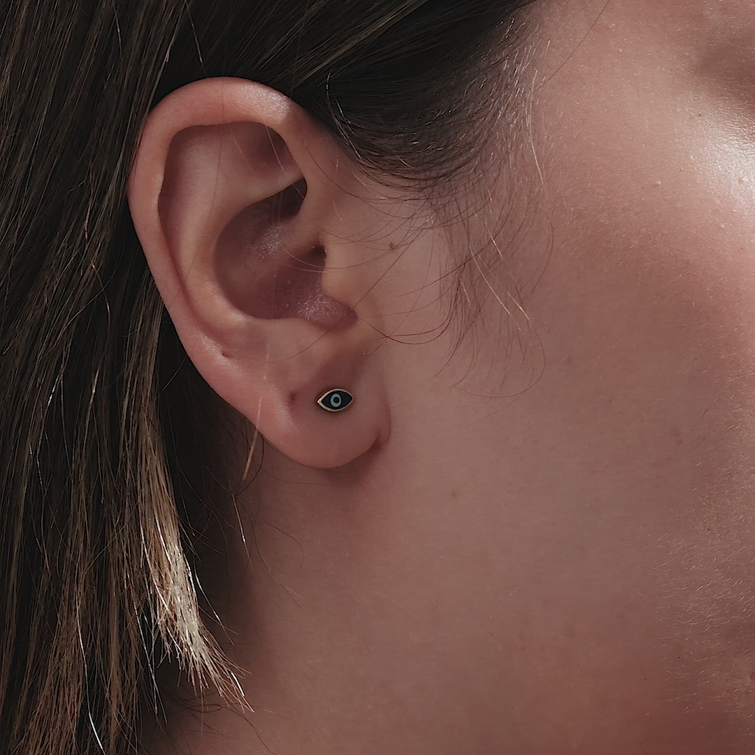 14K yellow gold minimalist evil eye stud earrings worn in ear, 7mm width, 3.5mm height, perfect for daily wear.