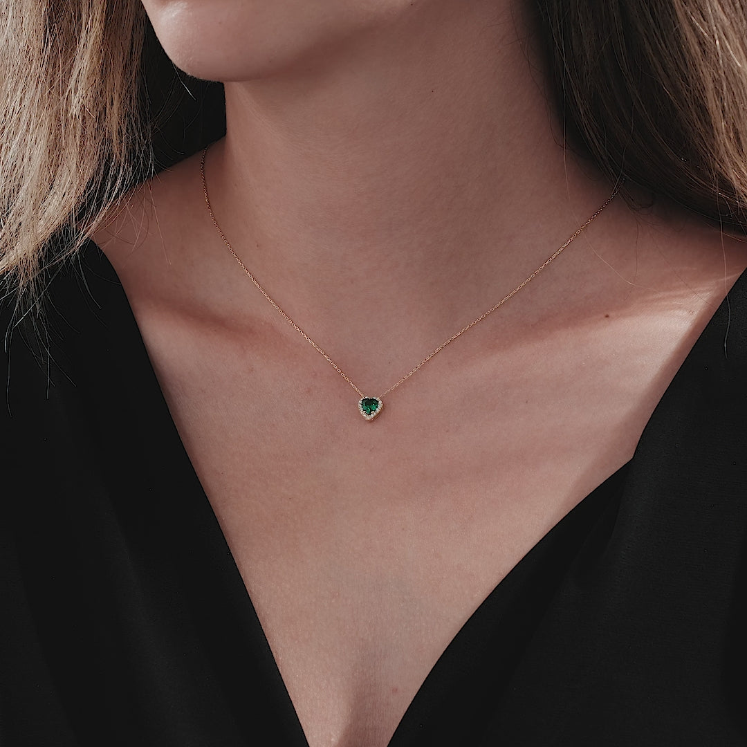 Dainty 14K yellow gold heart shape emerald necklace worn on a model.