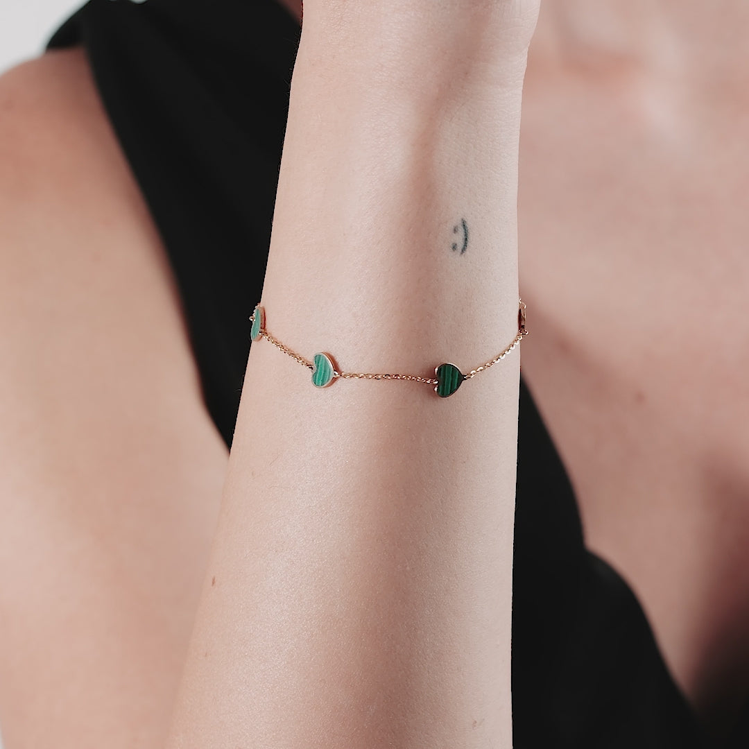 14K solid yellow gold bracelet featuring malachite hearts, elegantly worn on a model's wrist.