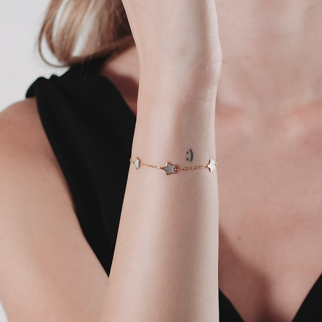 14K yellow gold mother of pearl star station bracelet worn on a woman's wrist, showcasing its delicate design.