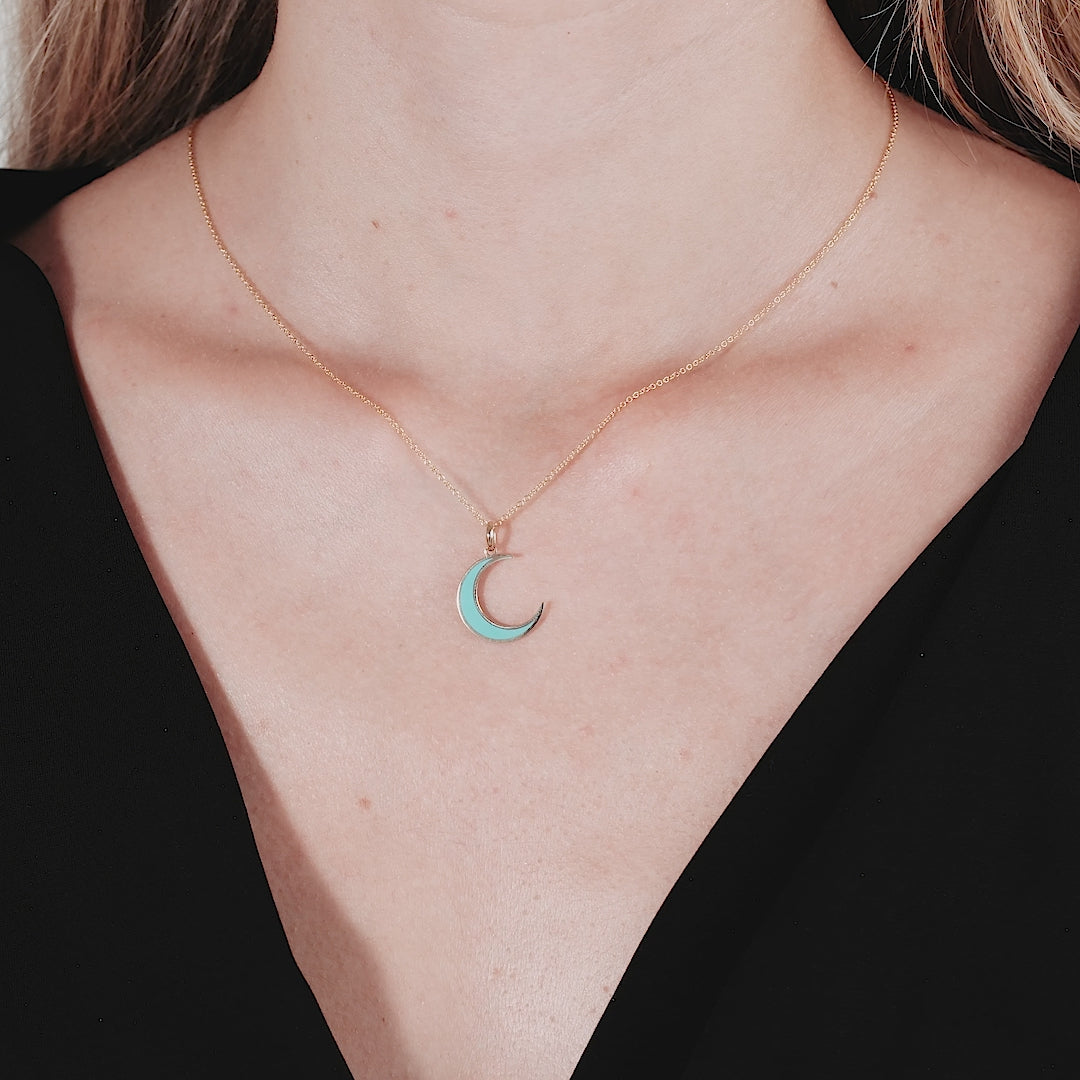 Dainty 14K yellow gold turquoise crescent moon necklace worn on a model's neck against a black top.