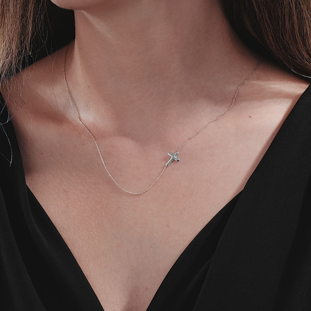 Dainty 14K solid white gold sideways cross necklace worn by a model, highlighting its minimalist design.