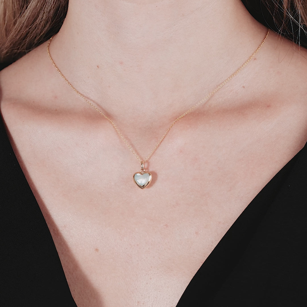 14K yellow gold mother of pearl heart necklace worn elegantly, featuring a dainty puffed heart pendant.