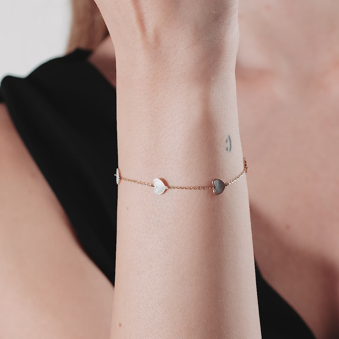 14K yellow gold station bracelet with mother of pearl hearts worn on wrist, elegant and simple design.