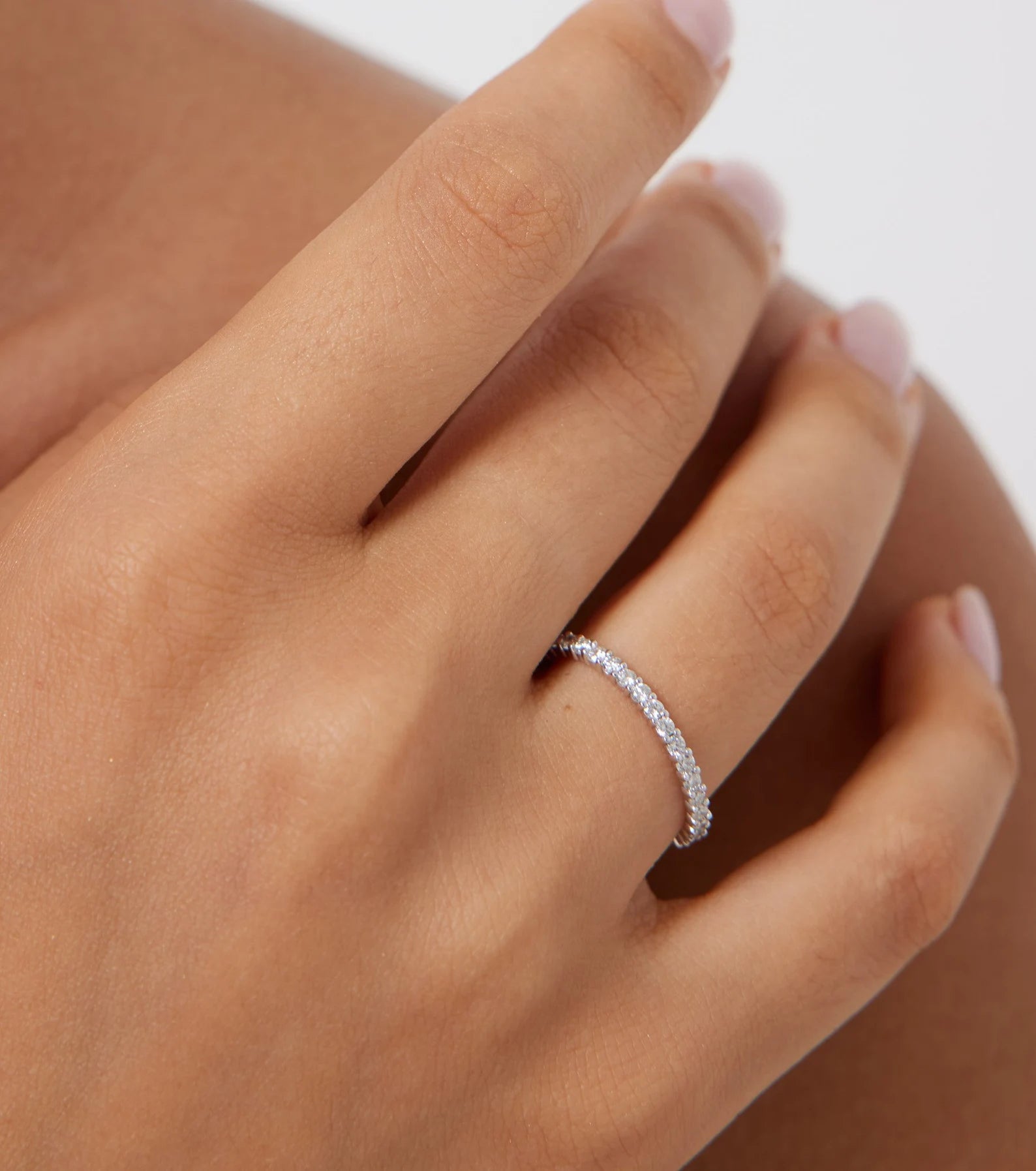 14K white gold eternity diamond ring on a hand, featuring 34 round diamonds with a shiny finish, perfect for weddings.
