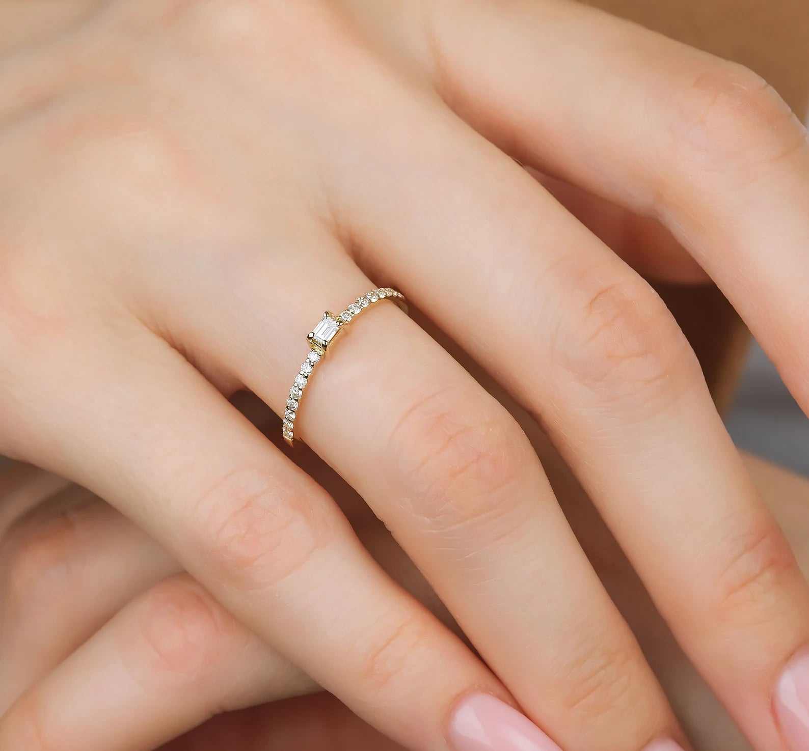 14K gold baguette diamond wedding ring on a woman's hand, featuring round diamonds and a simple elegant design.