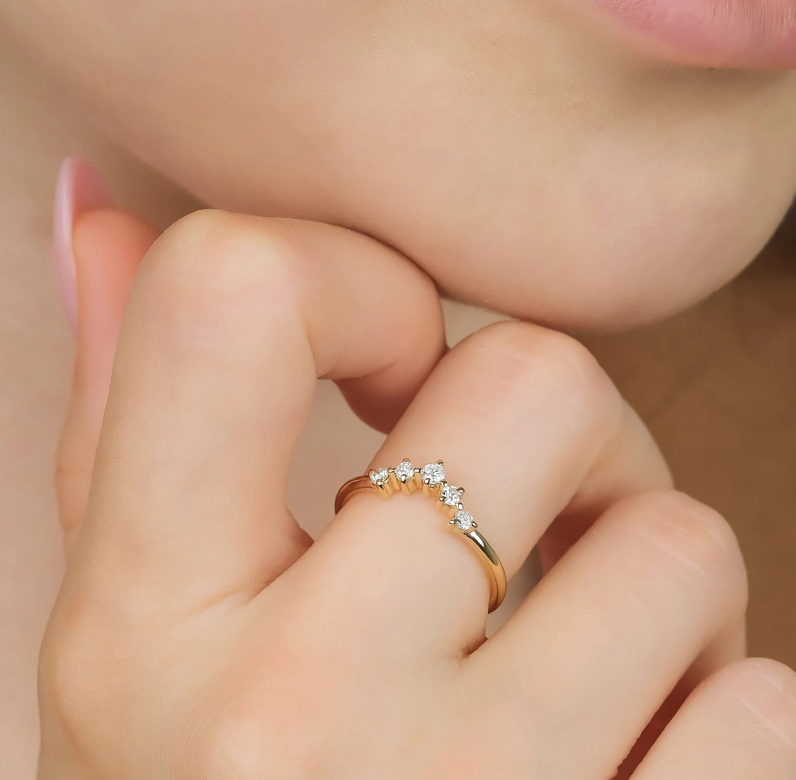 Close-up of a woman wearing a 14K gold curved diamond wedding ring with five sparkling diamonds.