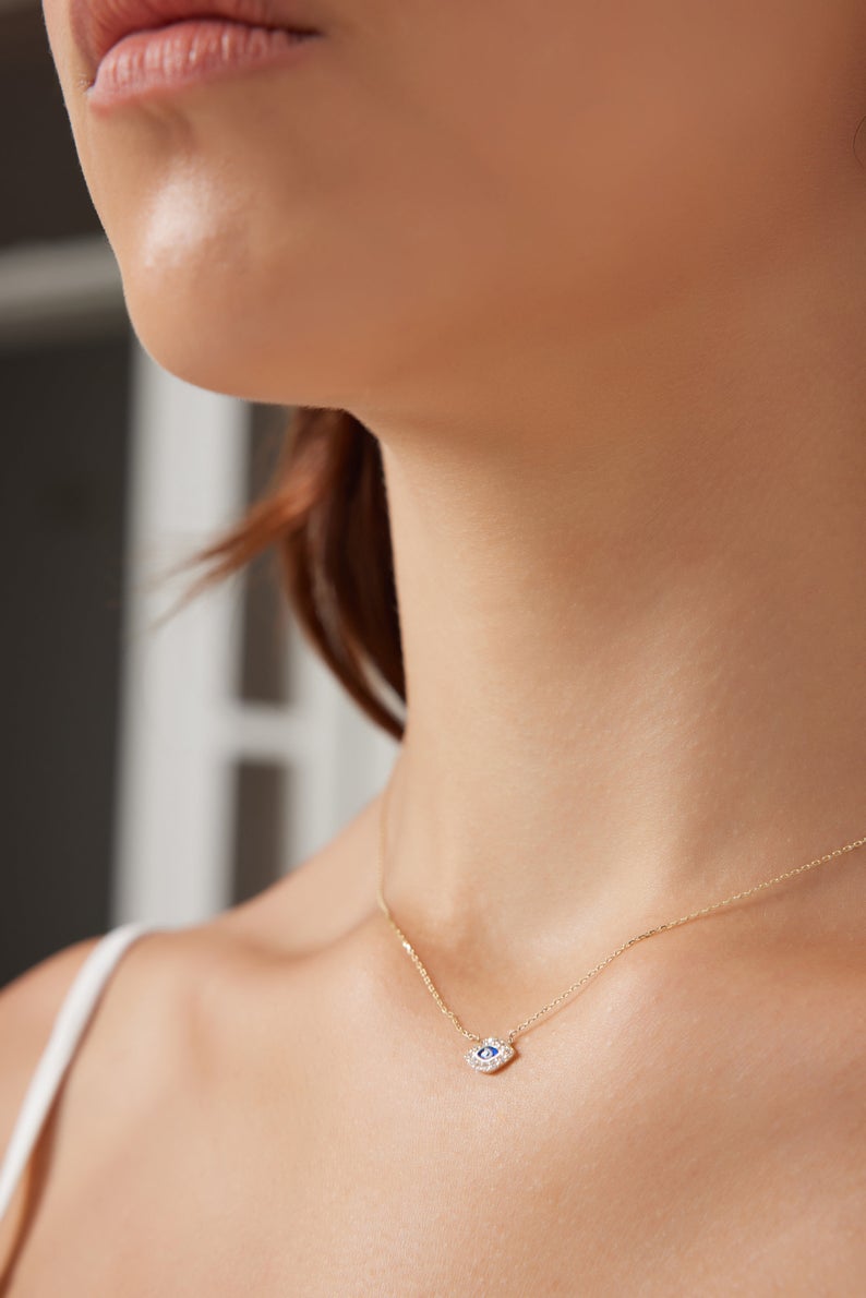 Model wearing a 14K solid yellow gold minimalist evil eye necklace with CZ, showcasing its elegant design.