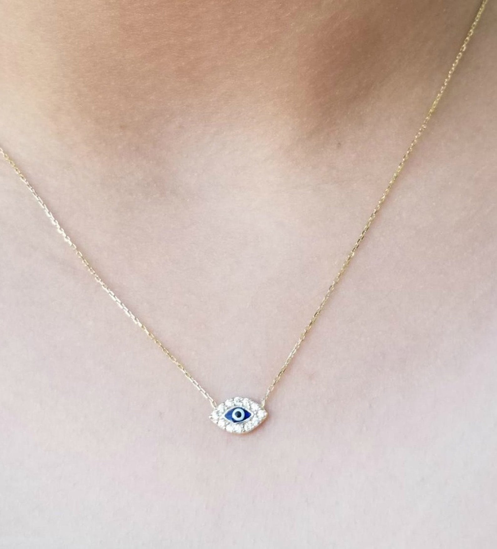 Minimalist 14K solid yellow gold evil eye necklace with CZ on a woman's neck.