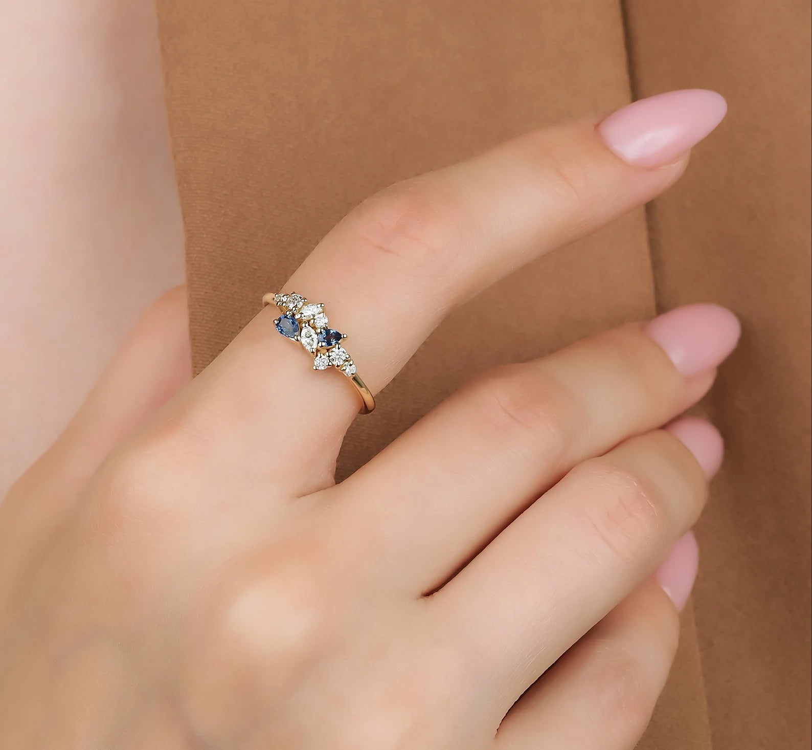 14K gold cluster ring with natural sapphire and marquise diamond worn on a hand, featuring a delicate design.