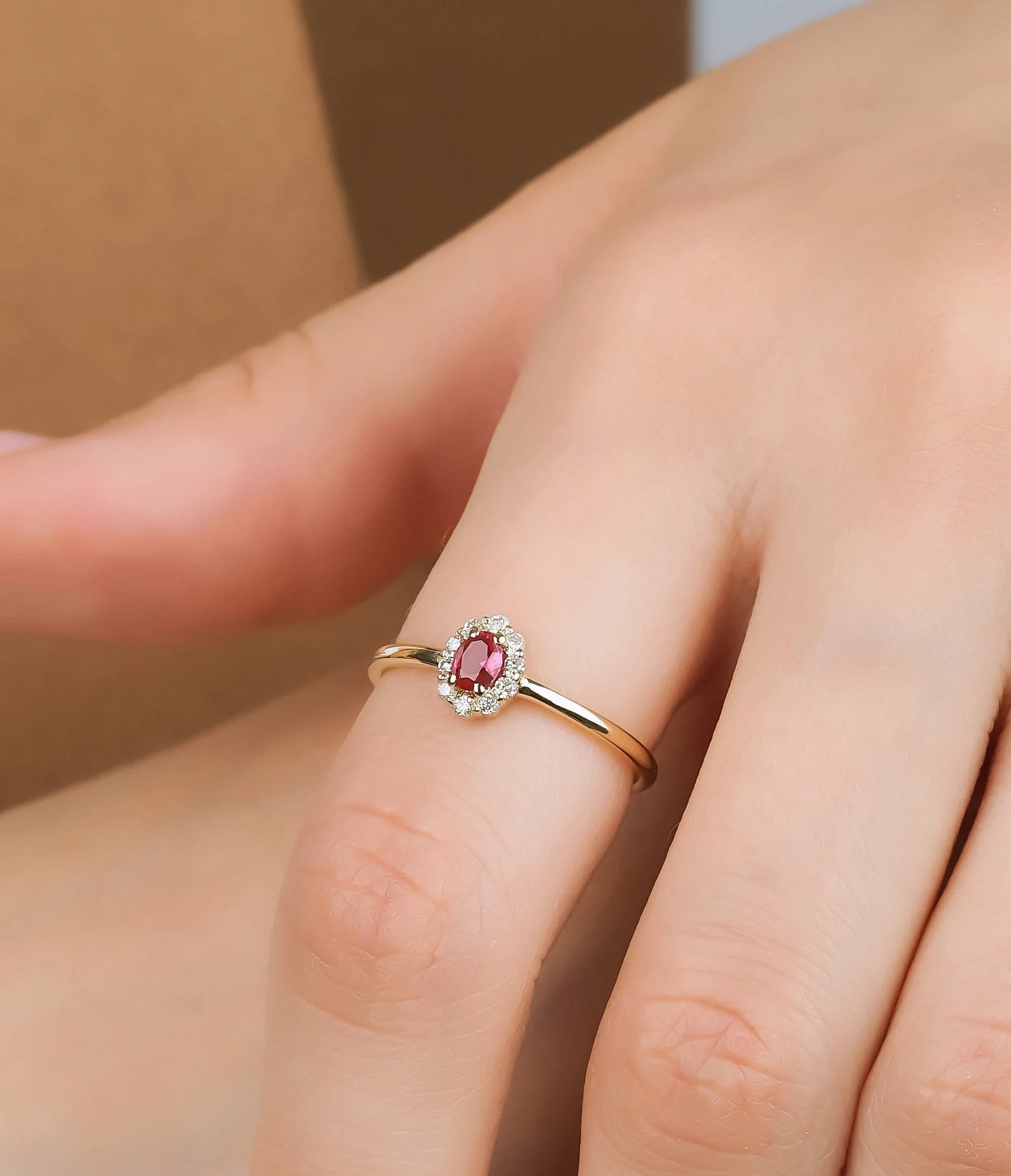 14K gold oval ruby and diamond ring worn on hand, showcasing its elegant design and vibrant gemstone.
