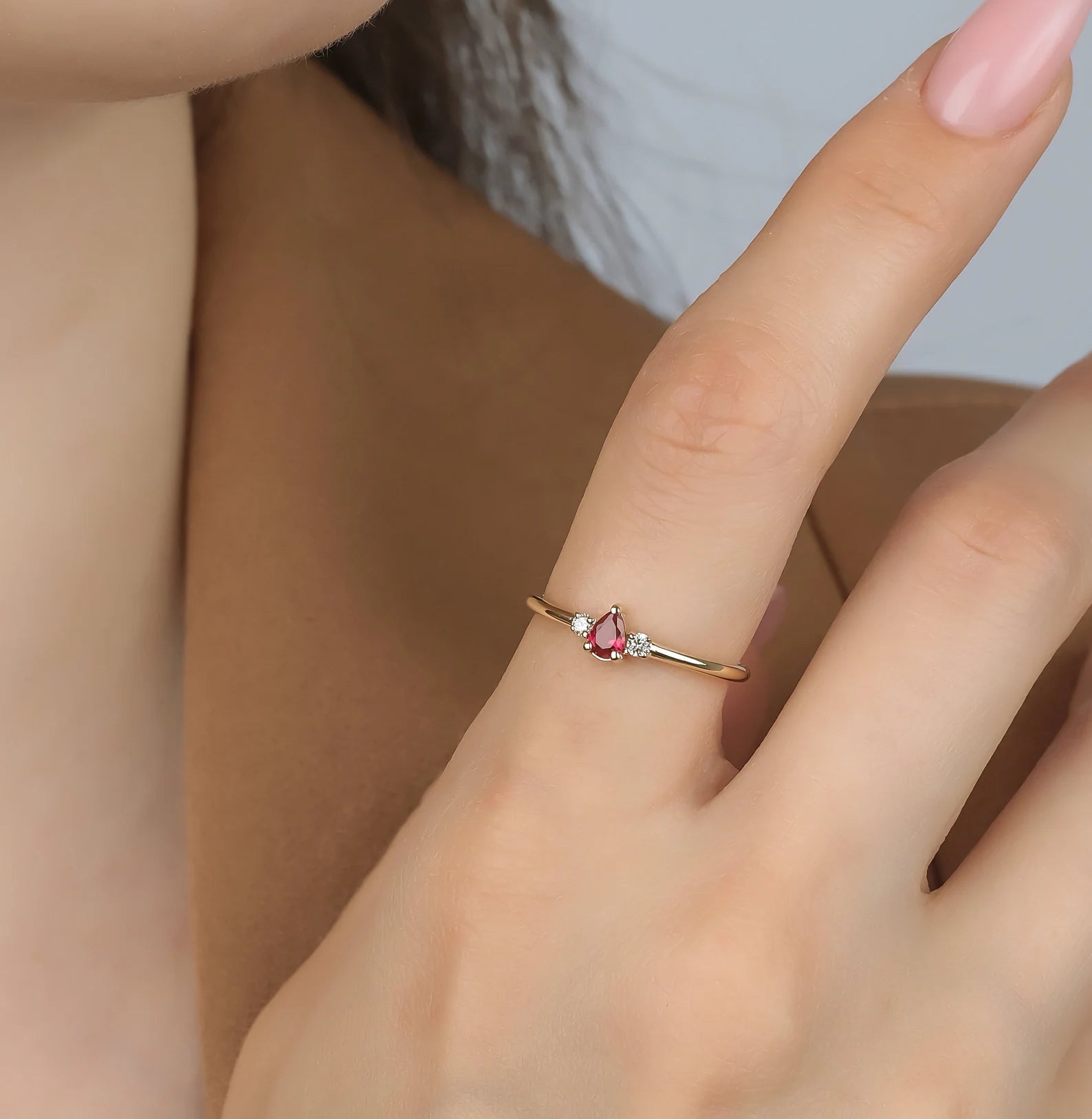 14K gold pear shape ruby and diamond ring worn on a woman's finger, showcasing elegant design and craftsmanship.