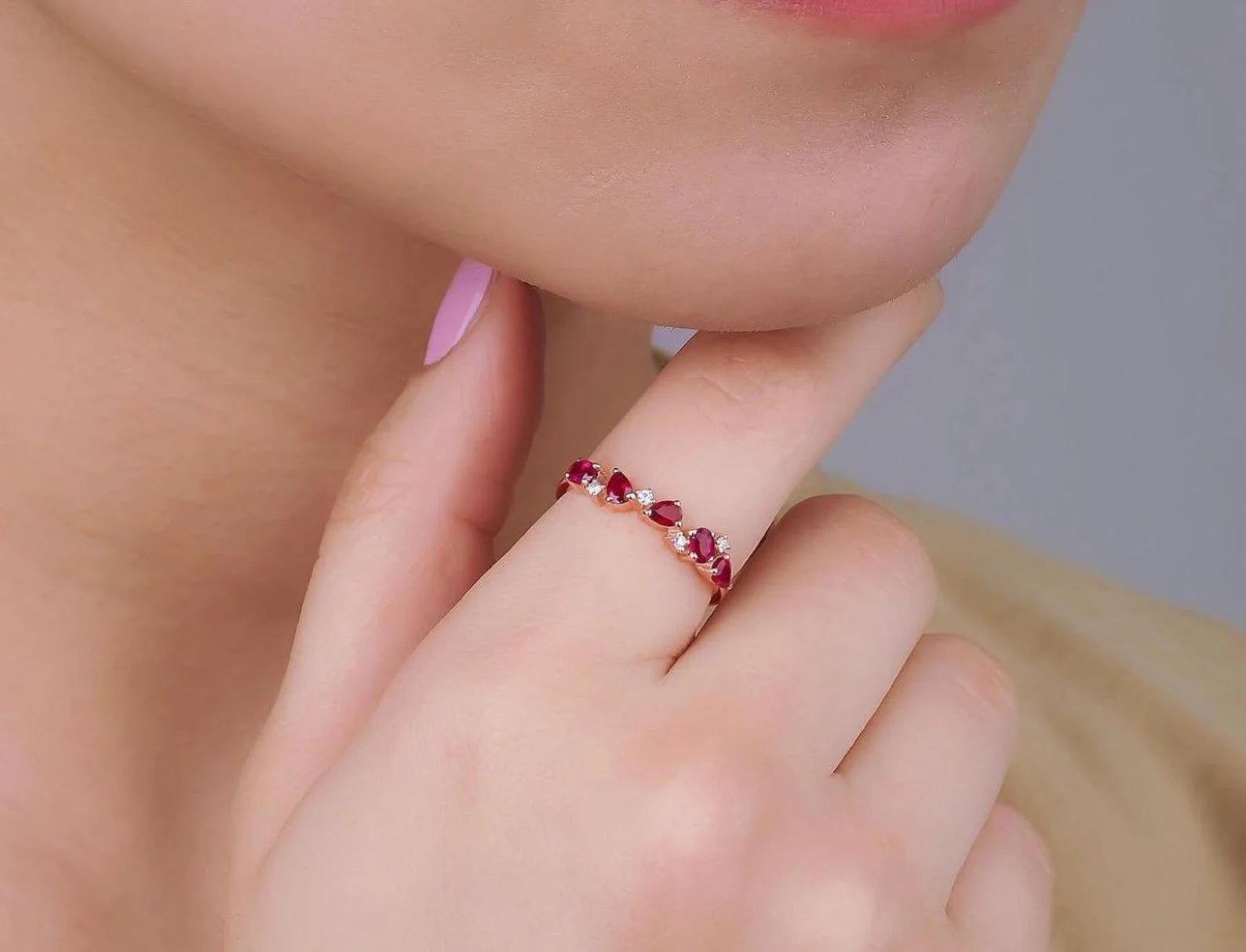 14K gold wedding ring featuring pear shape ruby and diamond, worn on a model's finger.
