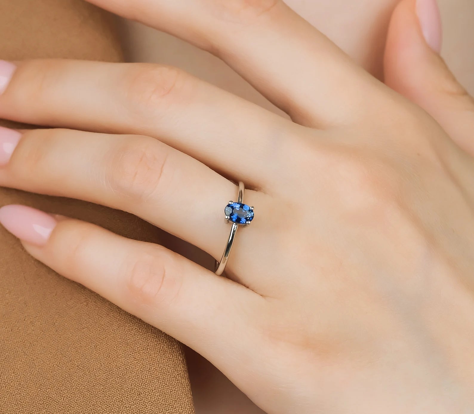 Delicate 14K solid yellow gold sapphire solitaire engagement ring worn on a hand, featuring a shiny finish and elegant design.