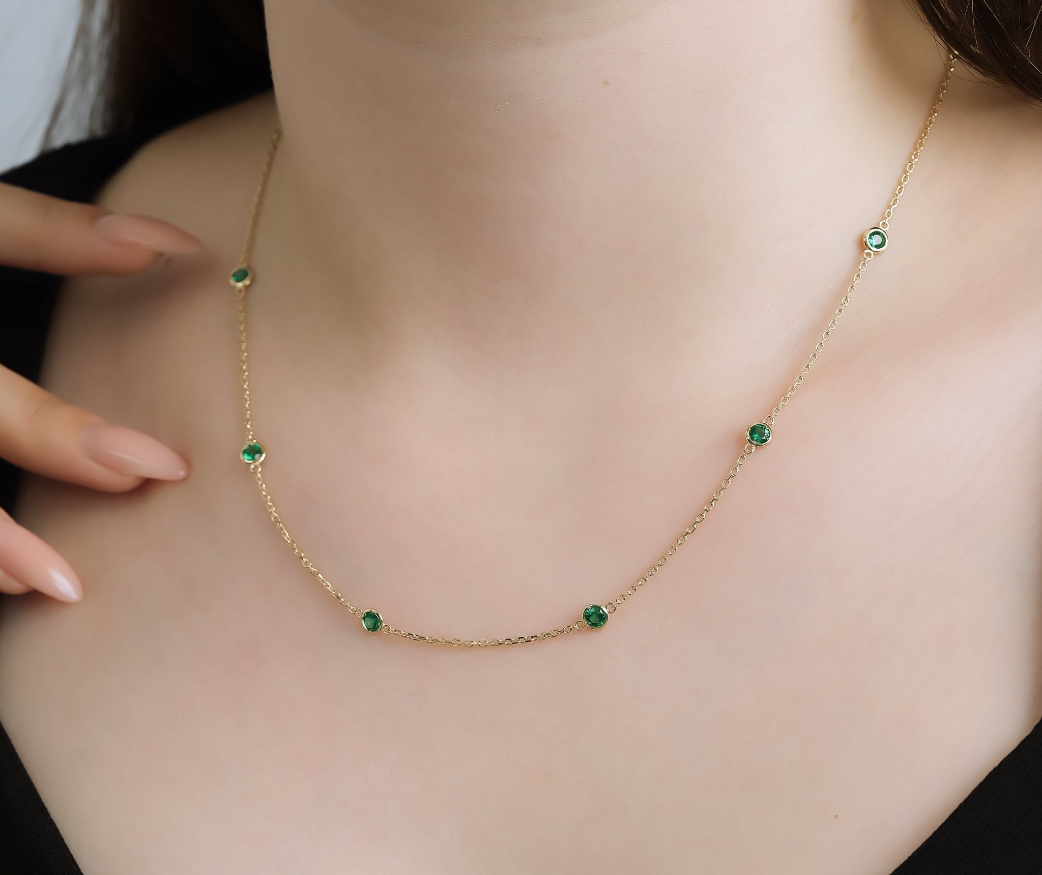 14K gold emerald station necklace showcased on a model, featuring dainty lab-created emeralds set in a delicate design.