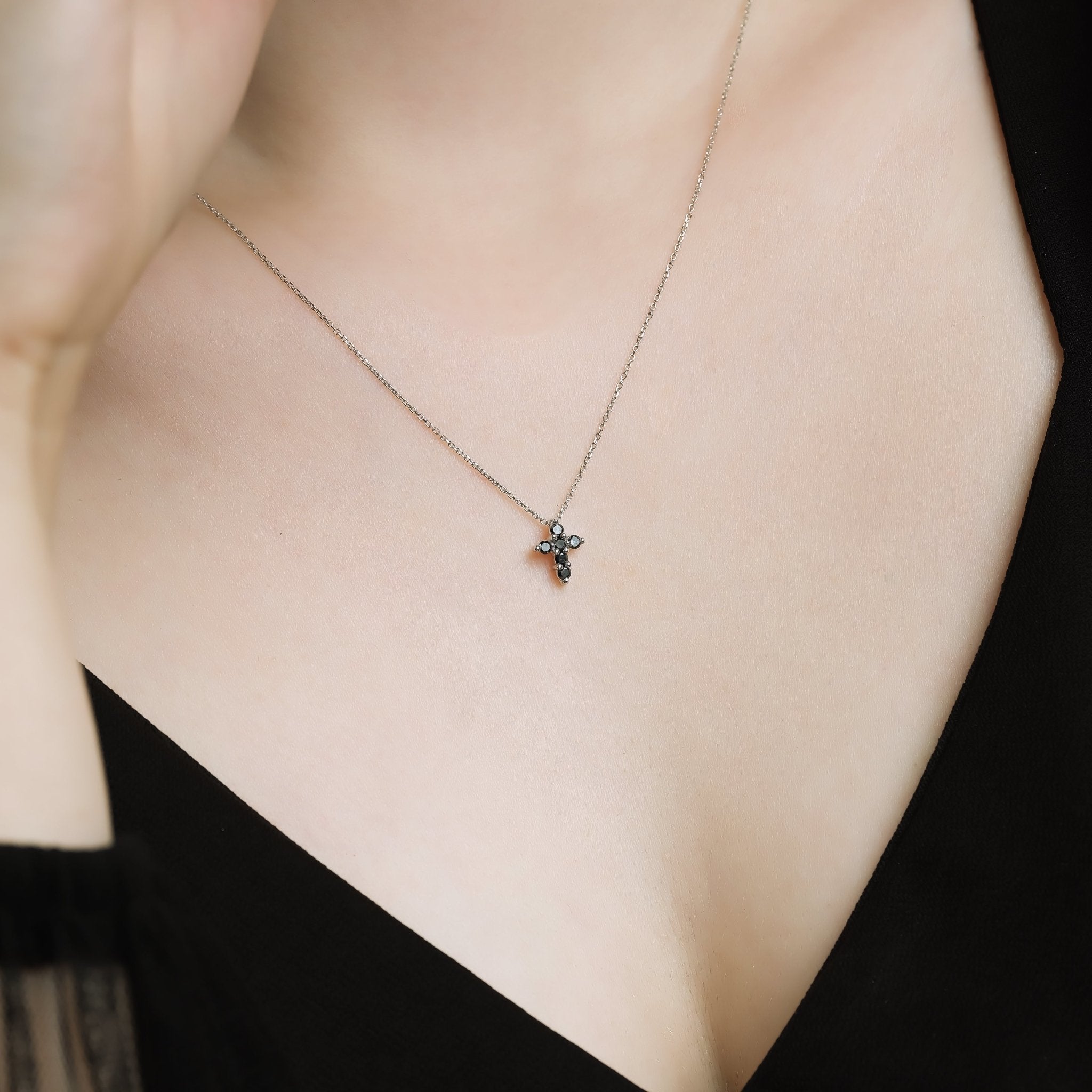 14K solid white gold minimalist cross necklace with black diamonds worn by a woman, showcasing elegant simplicity.