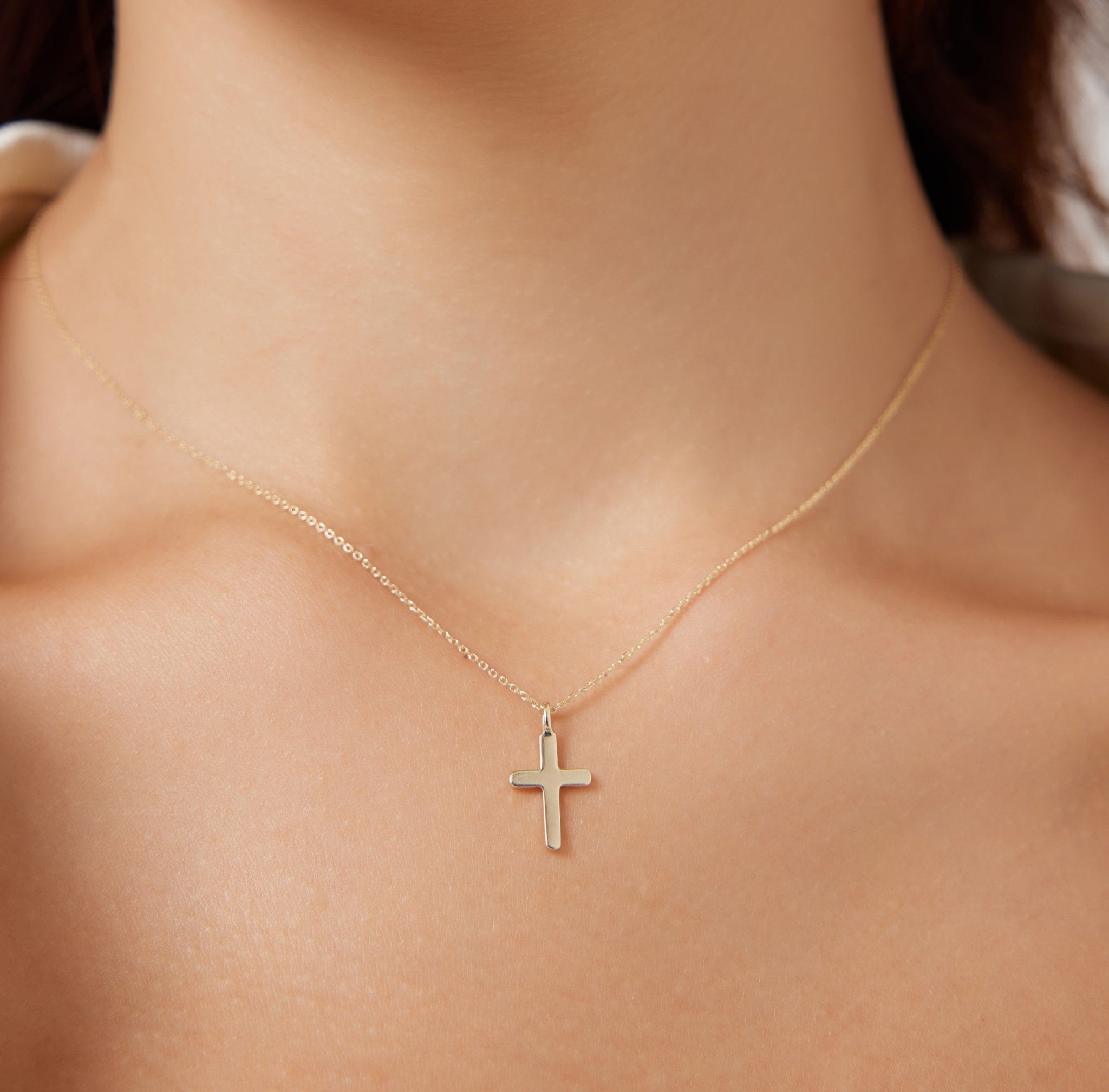 Minimalist 14K solid white gold cross necklace worn close up, highlighting its delicate design and elegance.