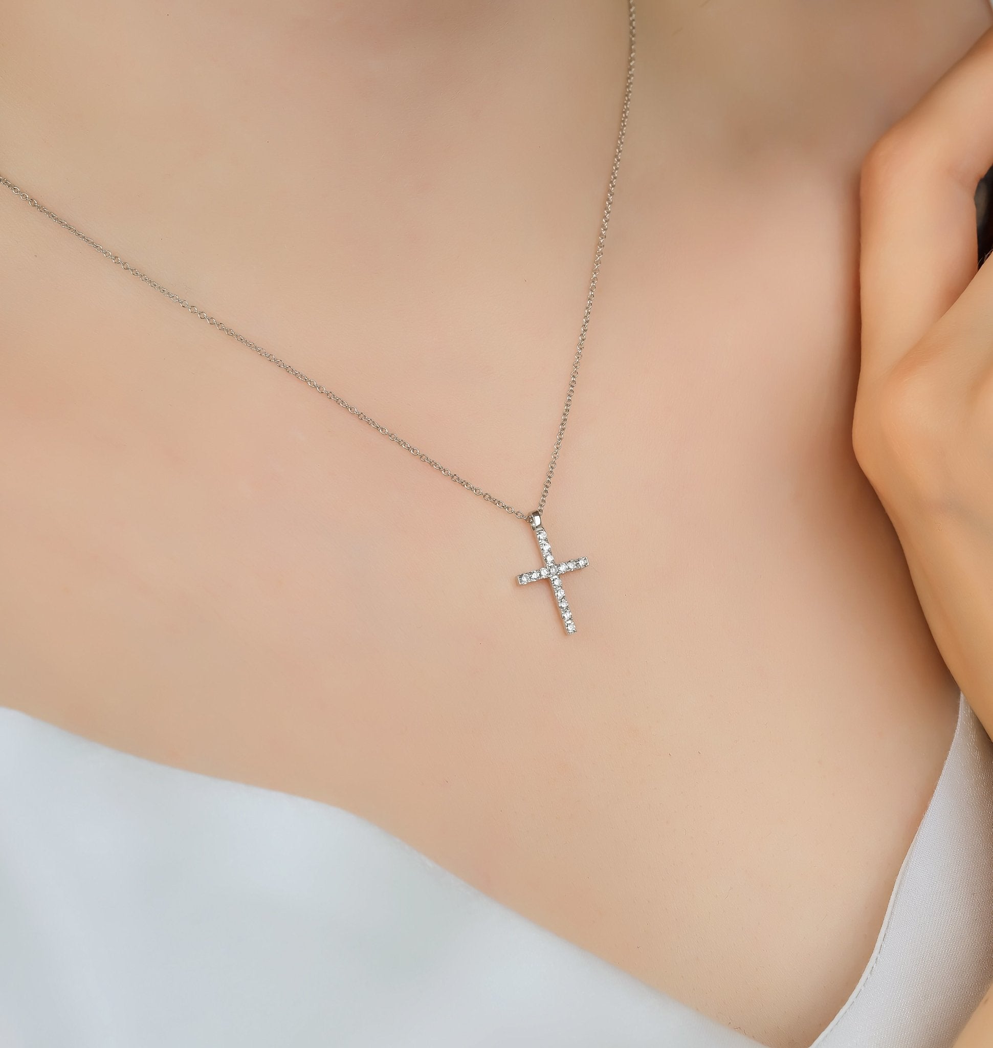 14K solid white gold cross necklace adorned with diamonds, worn elegantly around the neck, minimalist design.