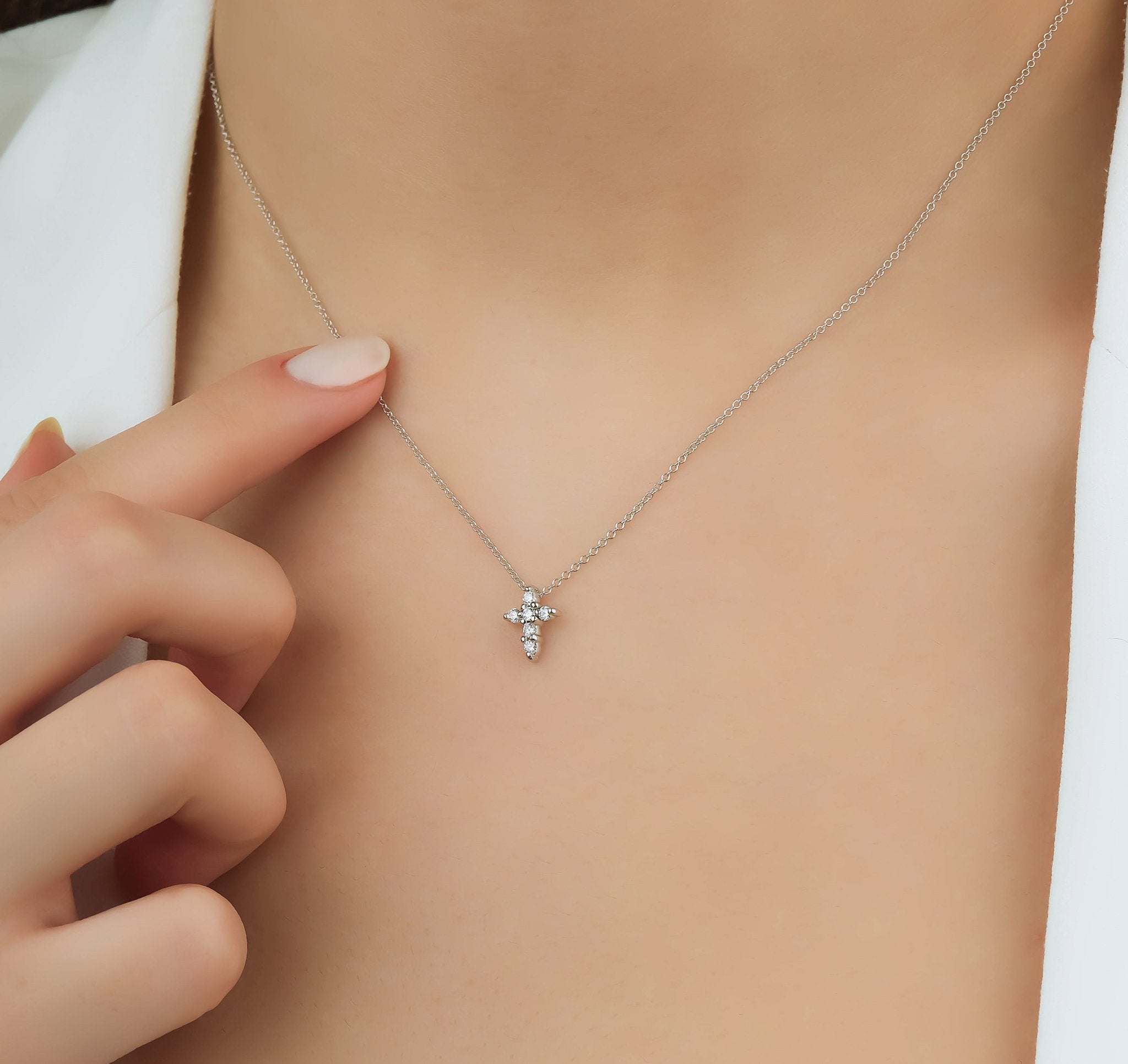 Dainty 14K white gold minimalist diamond cross necklace worn on model, highlighting elegance and simplicity.