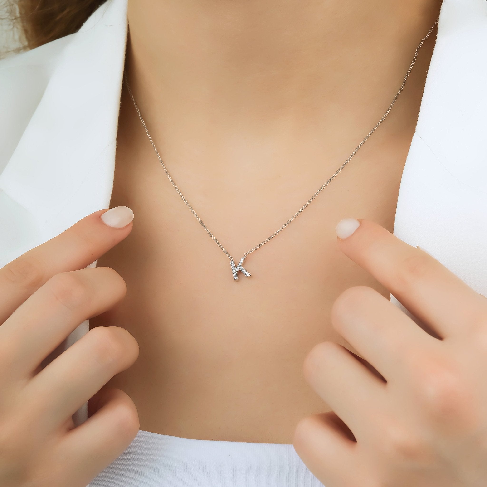 14K white gold diamond initial necklace featuring letter K, worn on a model, with delicate chain and sparkling diamonds.